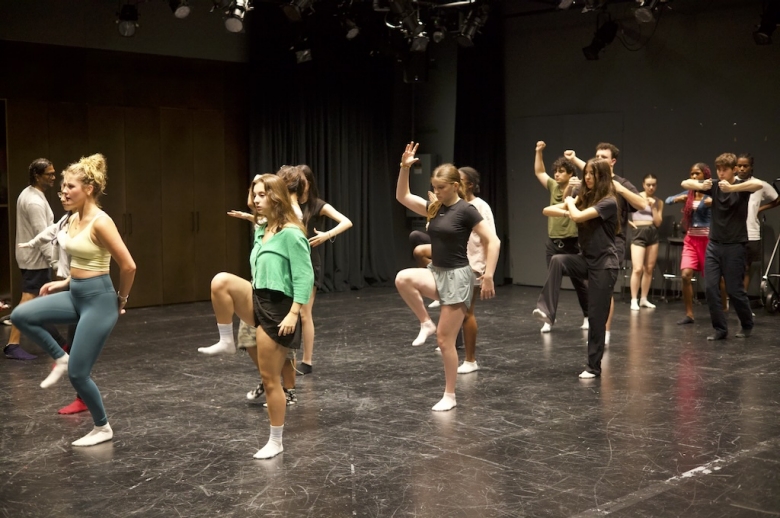 Group of Tisch Summer High School Drama students walking in a line with high knees and raised arms in mid-practice in a drama studio